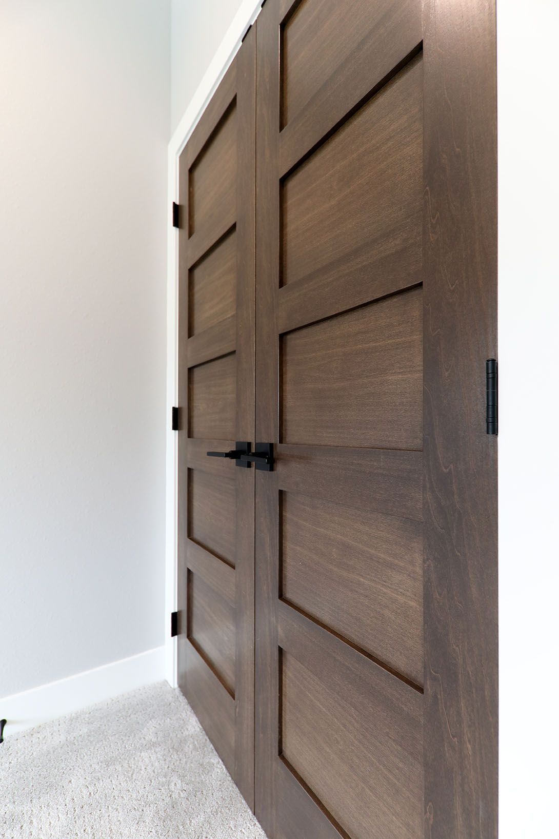 A pair of wooden doors with black handles in a room.