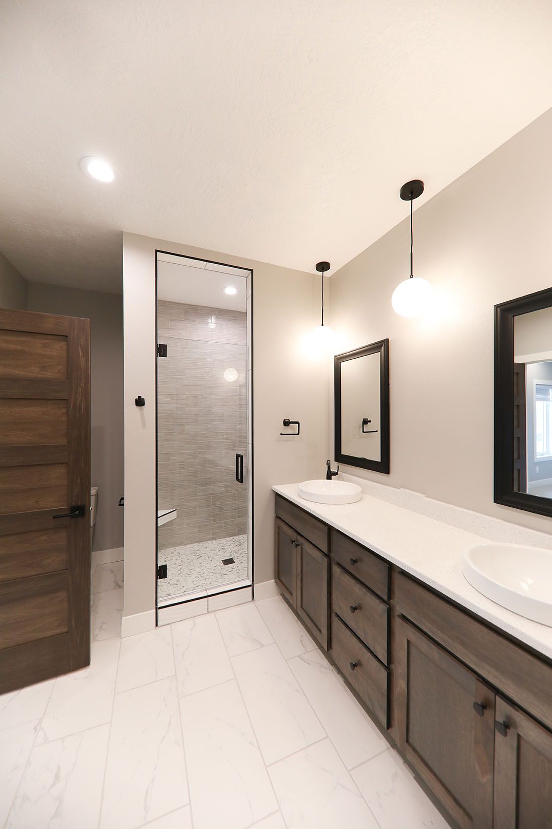 A bathroom with two sinks and a walk in shower.