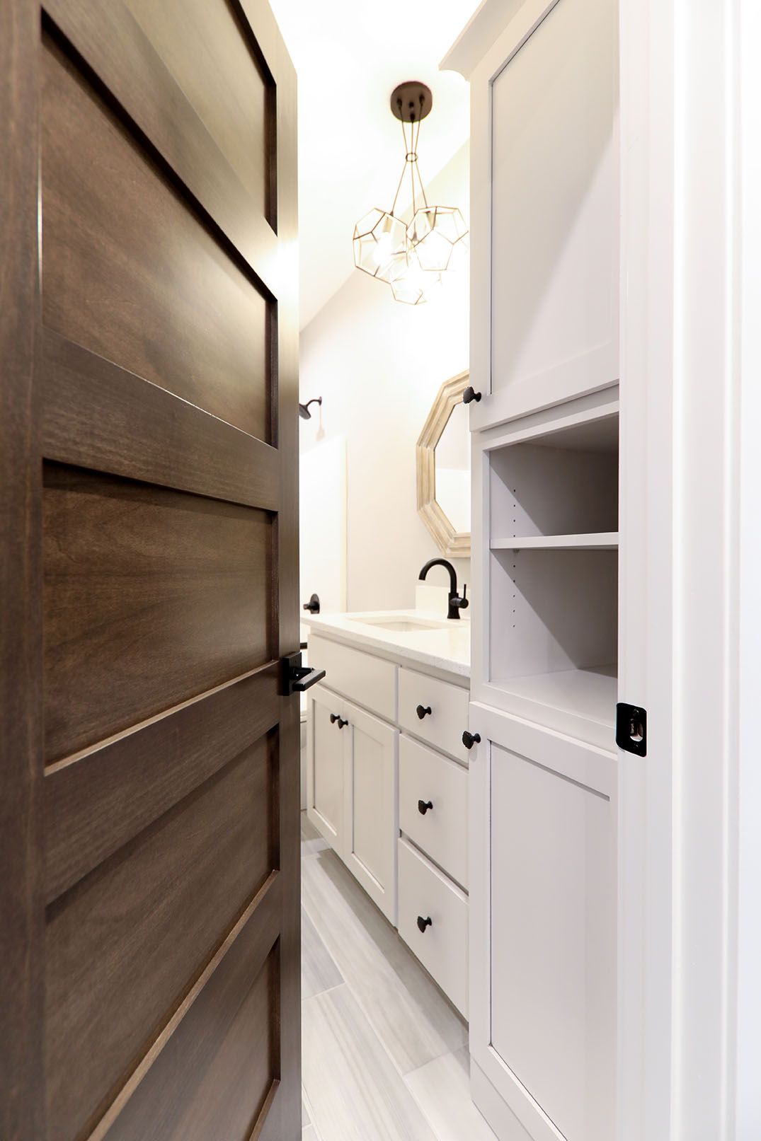 A bathroom with white cabinets and a wooden door