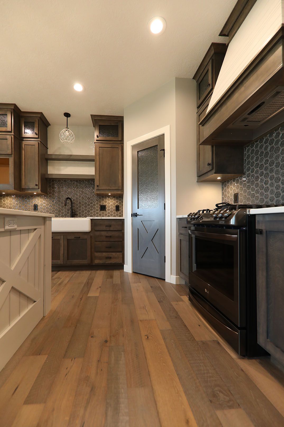 A kitchen with hardwood floors , a stove and a sink.