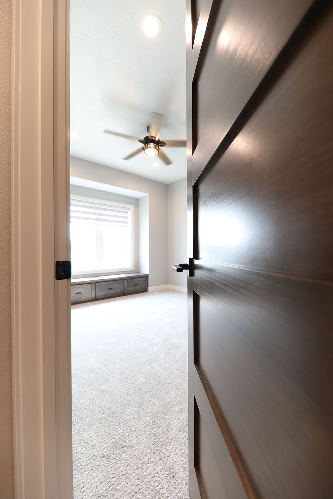 A bedroom with a ceiling fan and a window.
