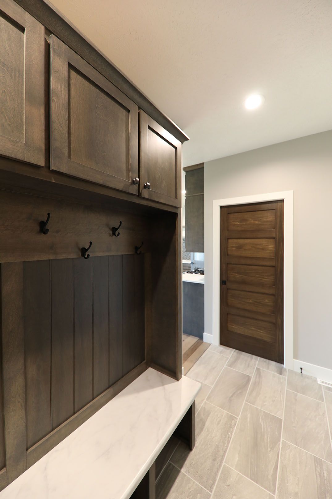 A hallway with a bench , cabinets and a door.