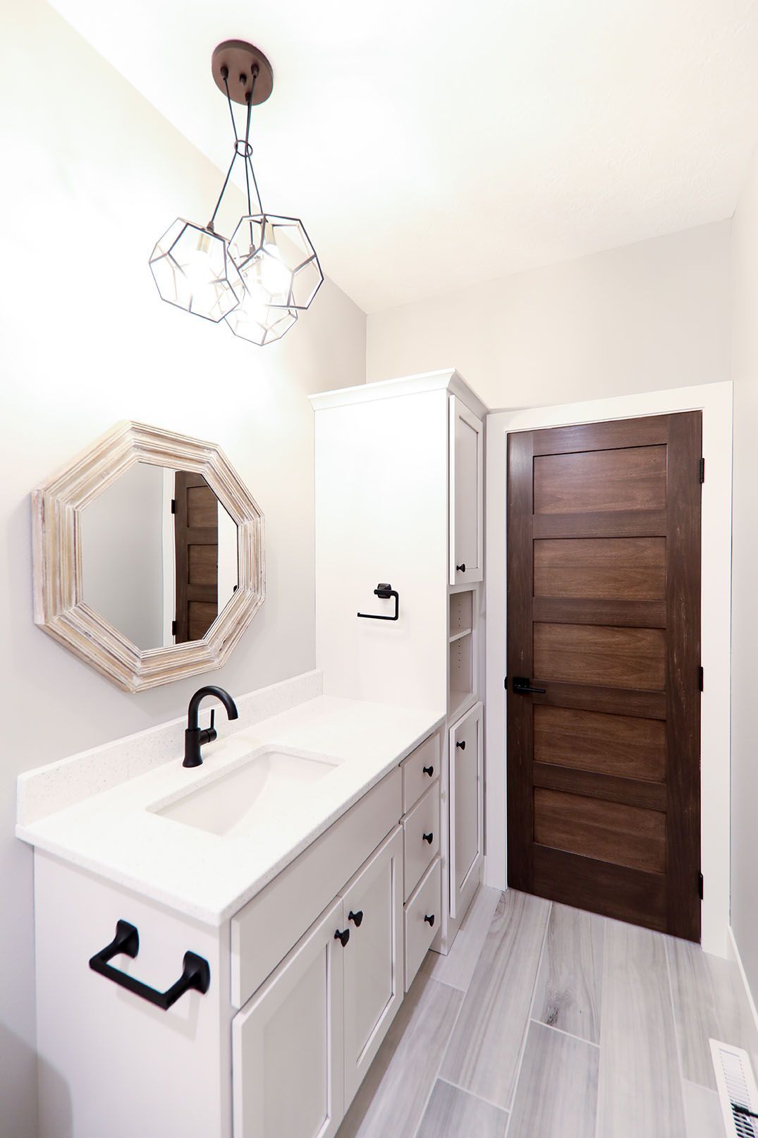 A bathroom with a sink , mirror and wooden door.