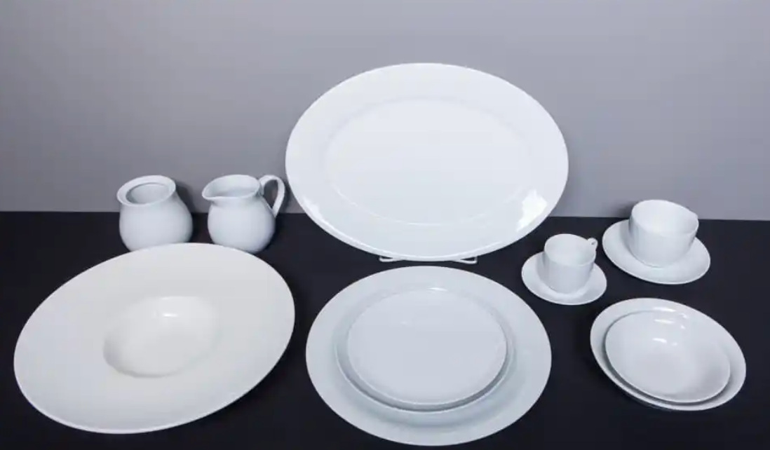 A table topped with a variety of white plates and bowls.