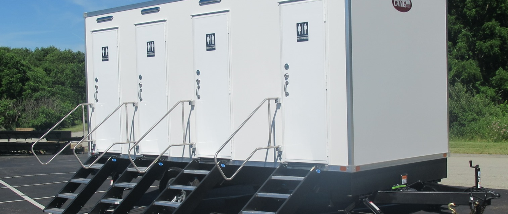 A row of white trailers with stairs attached to them are parked in a parking lot.