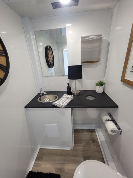 A bathroom with a sink, toilet and mirror.