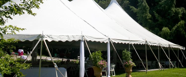 a large white tent is sitting in the middle of a grassy field .
