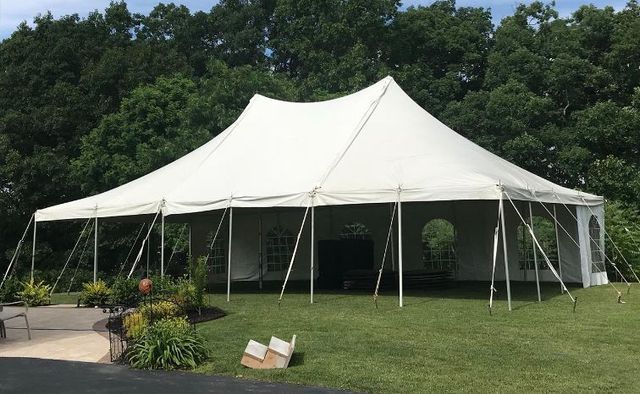 a large white tent is sitting in the middle of a grassy field .