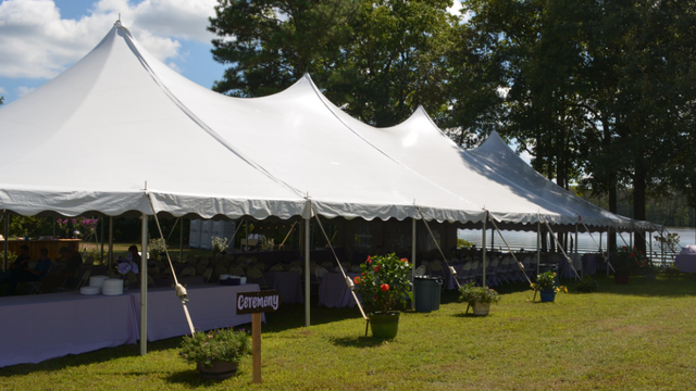 a large white tent is sitting in the middle of a grassy field .