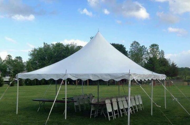 a white tent is sitting in the middle of a grassy field .