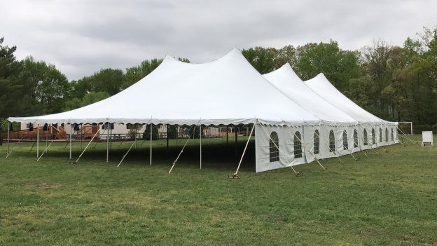 a large white tent is sitting in the middle of a grassy field .