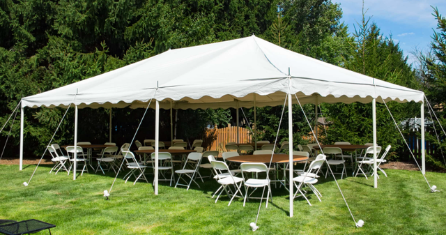 a large white tent with tables and chairs underneath it