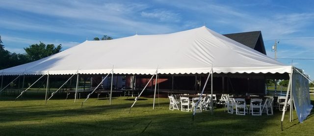 a large white tent is sitting in the middle of a grassy field .
