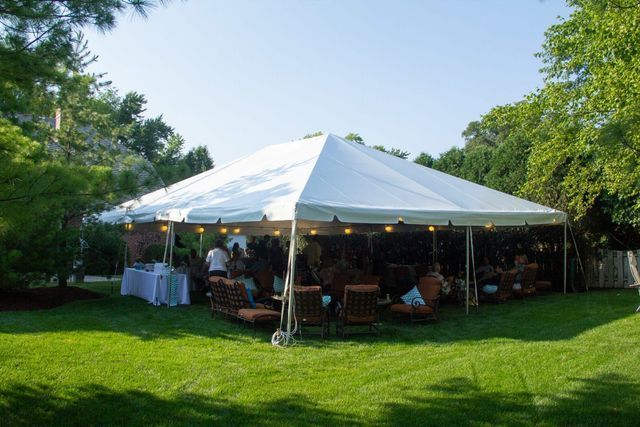 a large white tent is sitting in the middle of a lush green field .