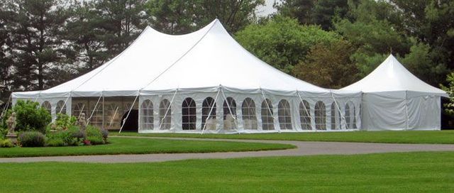 a large white tent is sitting in the middle of a grassy field .