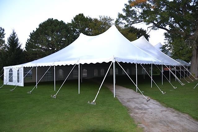 a large white tent is sitting in the middle of a grassy field .