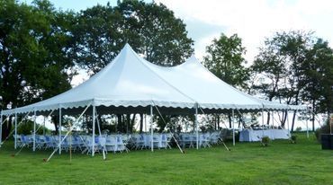 a large white tent is sitting in the middle of a grassy field .
