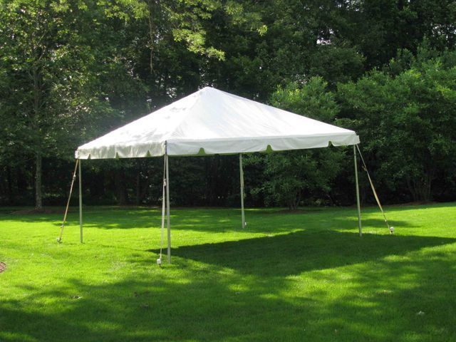 a white tent is sitting in the middle of a lush green field .
