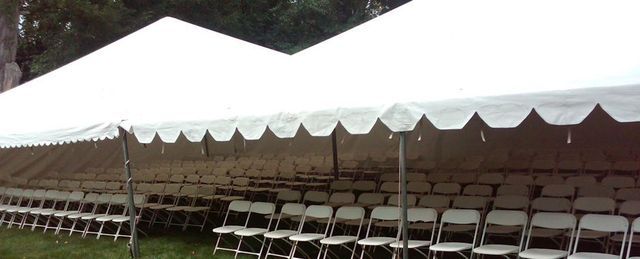 a row of folding chairs under a white tent .