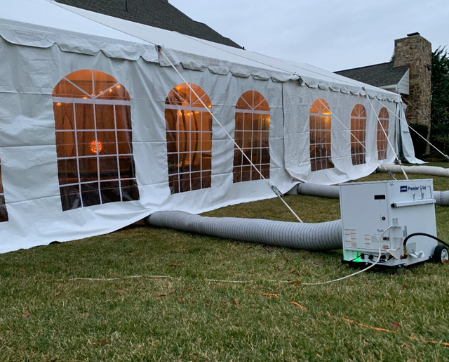 a large white tent is sitting on top of a lush green field .