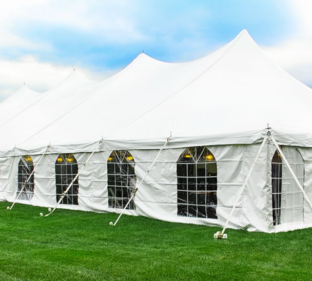 a large white tent is sitting on top of a lush green field .