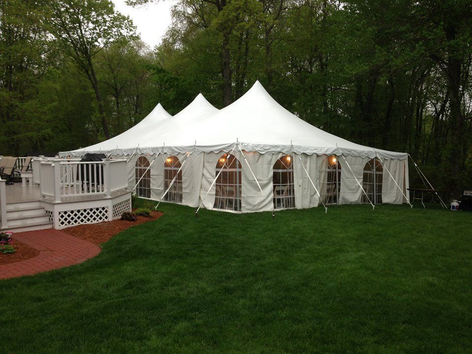 a large white tent is sitting in the middle of a lush green field .