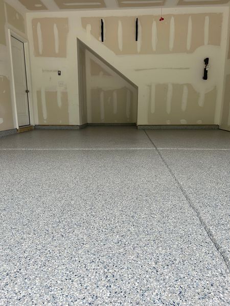 Garage interior with gray speckled epoxy floor and unfinished walls.