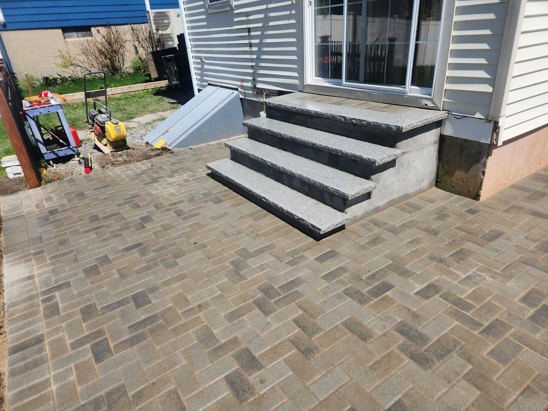 Back patio with gray steps, brick pavers, and a small playground area beside the house