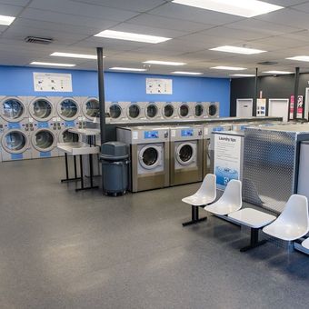 A laundromat with a lot of washing machines and chairs