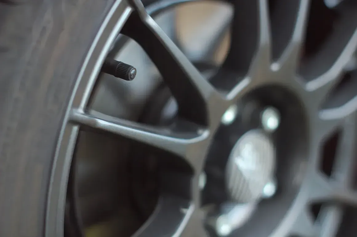 Close-up of a dark gray car wheel with the valve stem in focus.