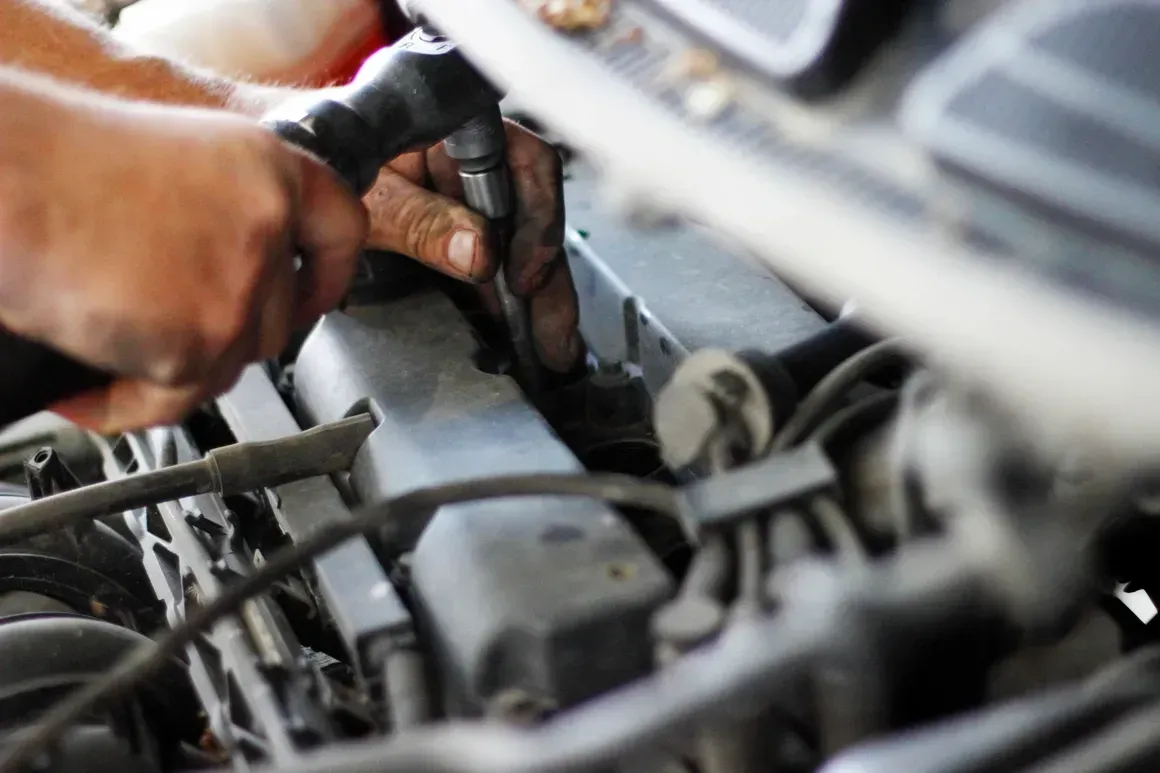 Hands working on a car engine, using a wrench.