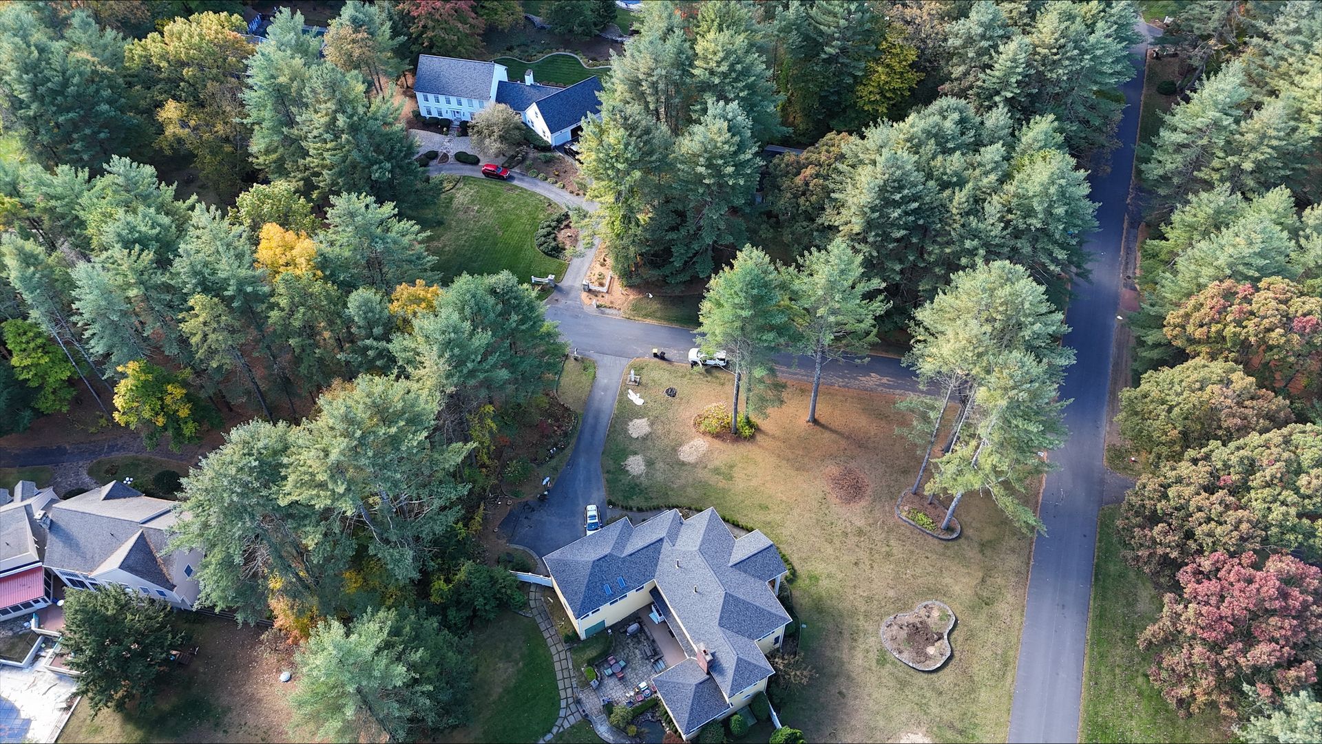 An aerial view of a house in the middle of a forest surrounded by trees.