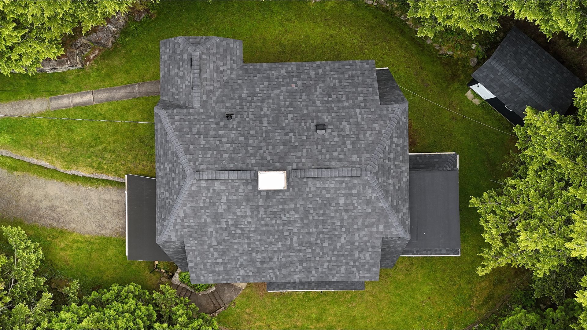 An aerial view of a house surrounded by trees and grass.