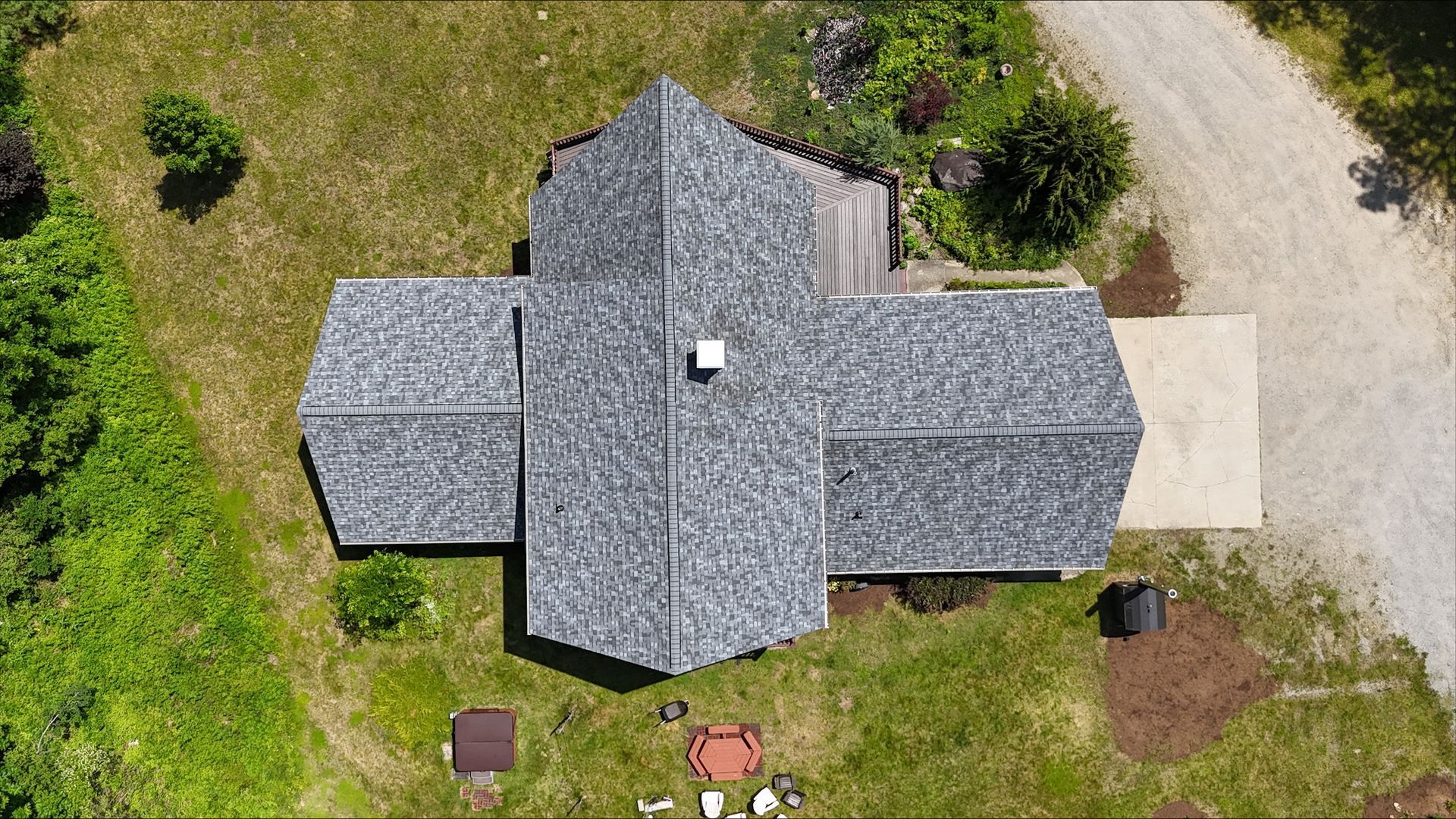 An aerial view of a house with a gray roof and a driveway.