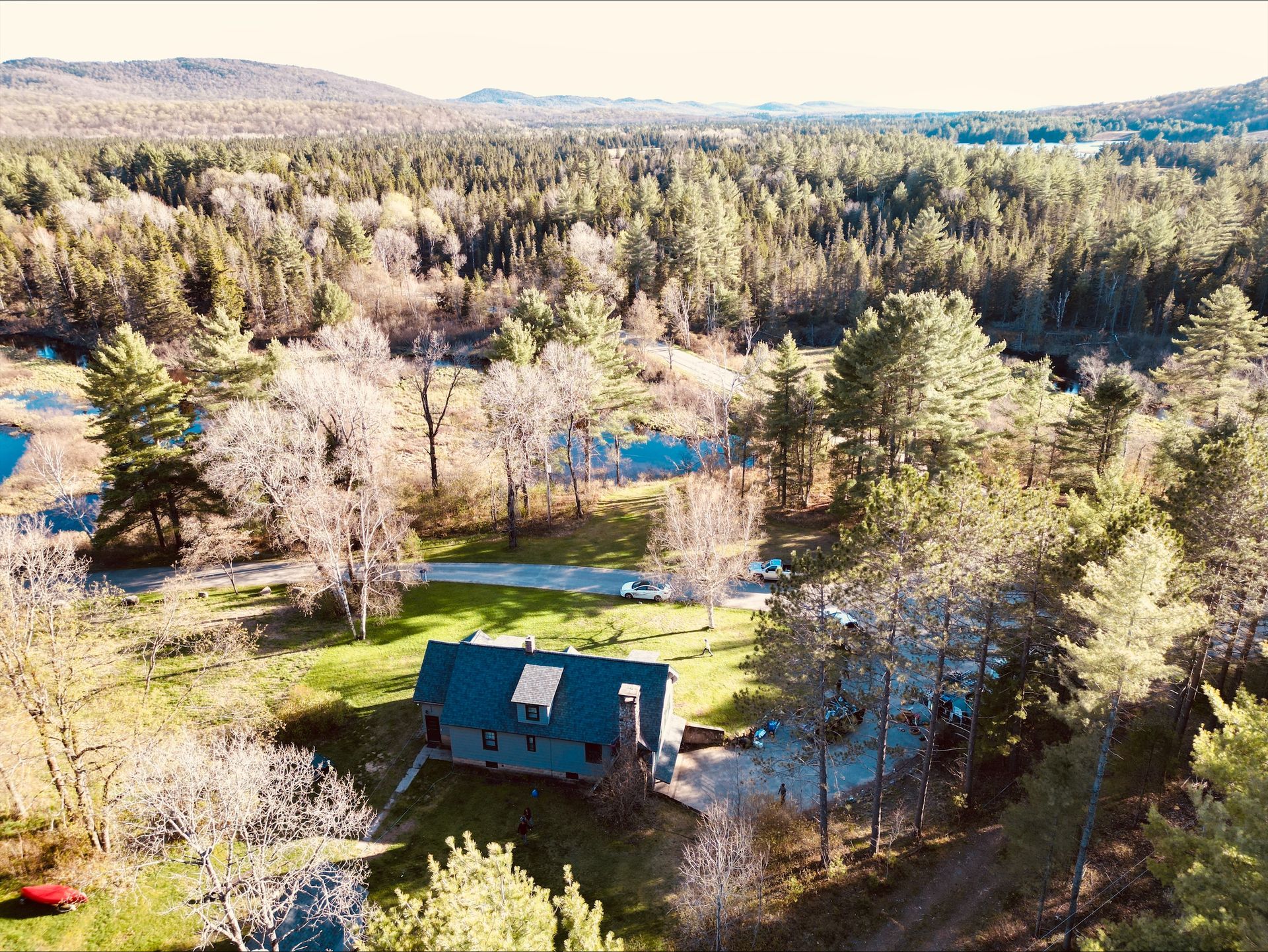 An aerial view of a house in the middle of a forest surrounded by trees.
