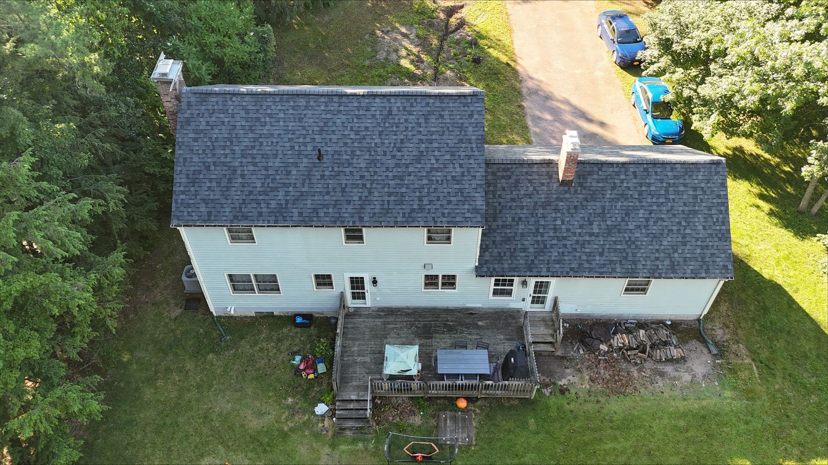 An aerial view of a white house with a blue car parked in front of it.
