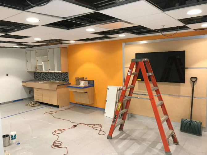 Room under construction with orange walls, a ladder, and a large TV.