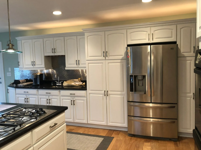 Kitchen with white cabinets, stainless steel appliances, and black countertop.