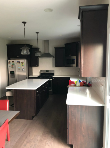Dark wood kitchen with white countertops and stainless steel appliances.