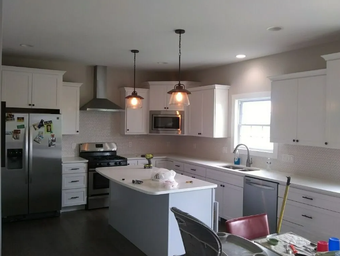 Modern kitchen with white cabinets, stainless steel appliances, and a gray island.