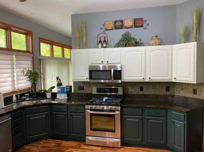 Kitchen with dark green and white cabinets, stainless steel appliances, and dark countertops.
