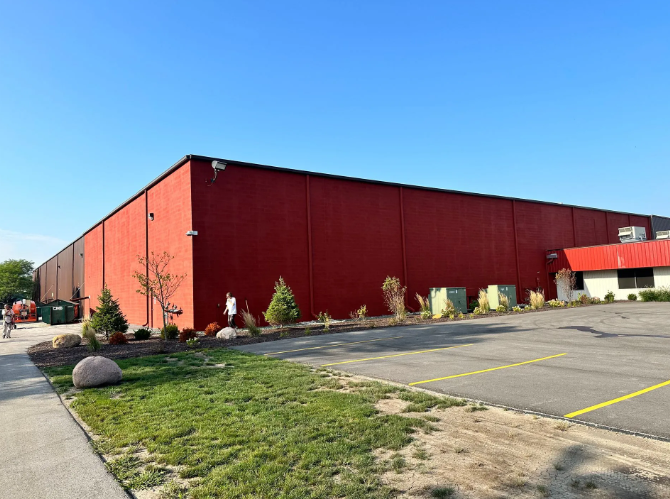 Red industrial building with parking lot and small landscaping.