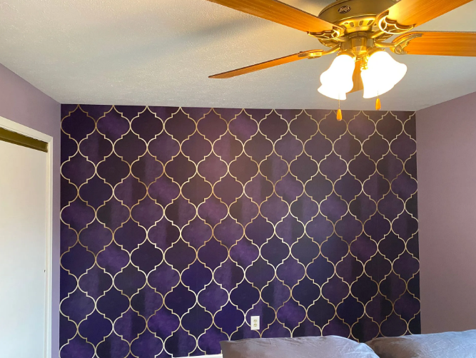 Purple accent wall with gold quatrefoil design; light fixture and ceiling fan visible.