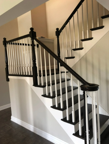 Staircase with black railings and white balusters. Steps are painted black and white.