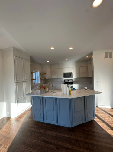 Kitchen with blue island, white cabinets, and wooden floors.