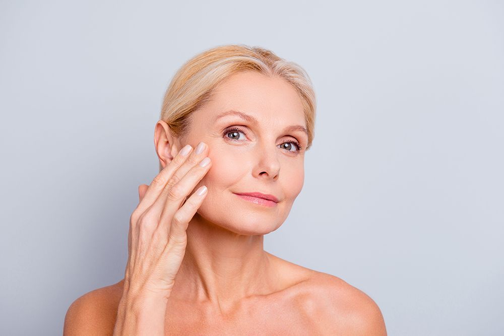 A woman is touching her face with her hand and smiling