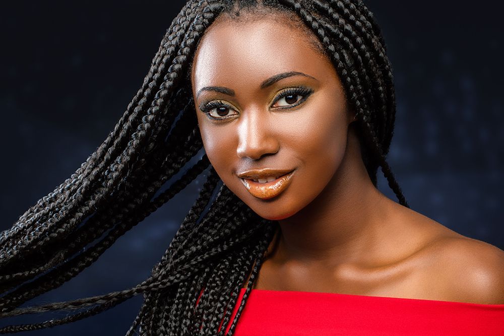 A woman with braids is wearing a red off-the-shoulder top