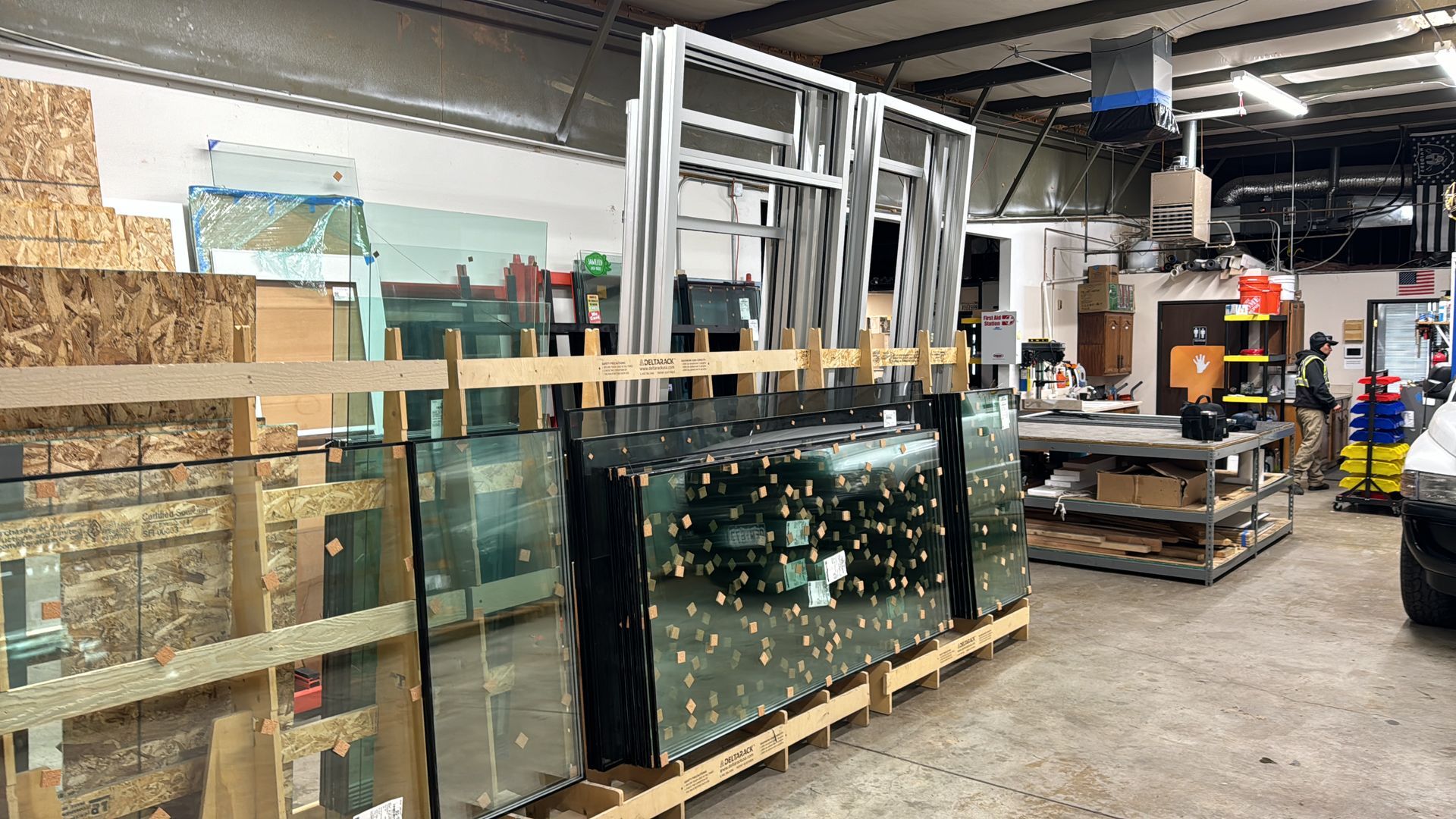 Warehouse interior with stacks of glass panes and window frames.