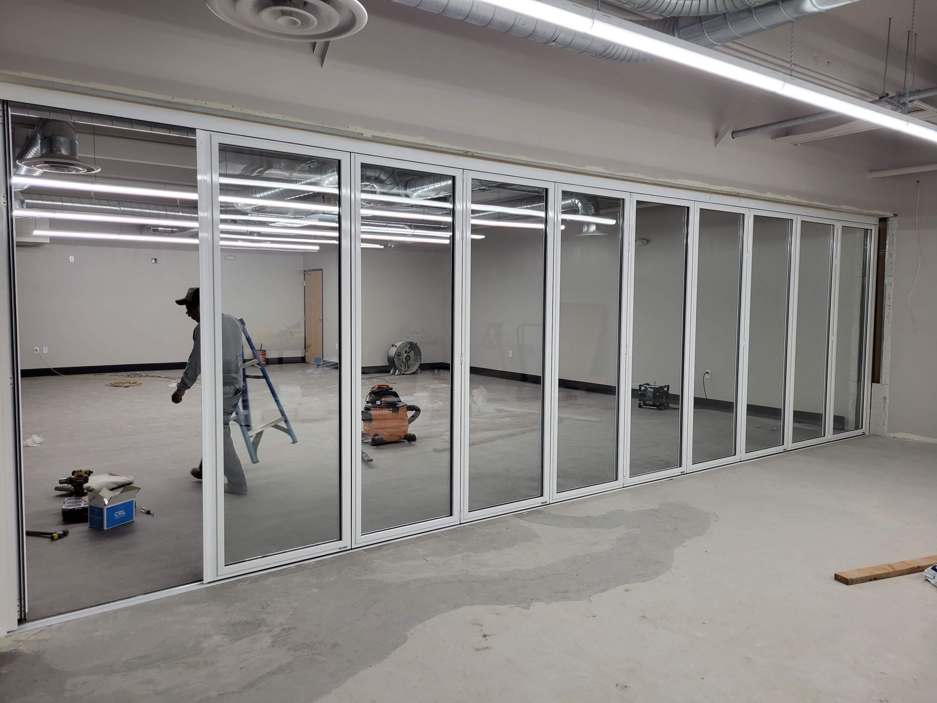 Interior view of room with accordion-style glass doors. A person works inside.