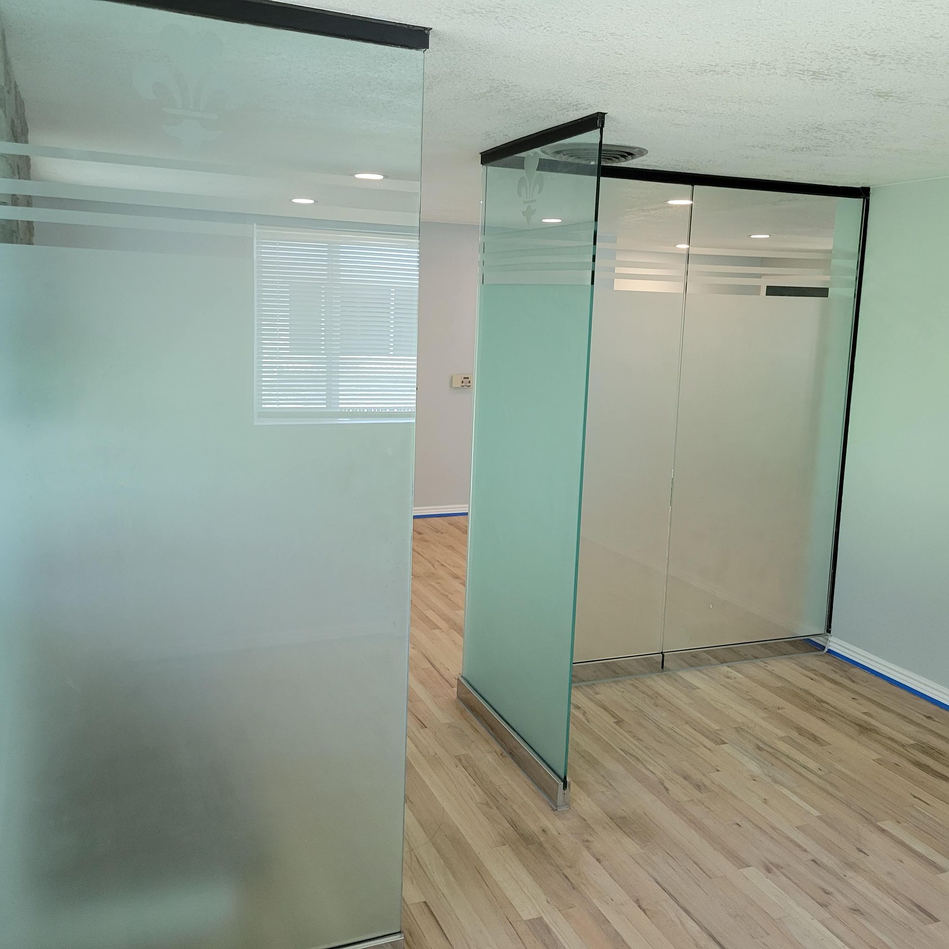Interior view of office space with frosted glass partitions and wooden floors.